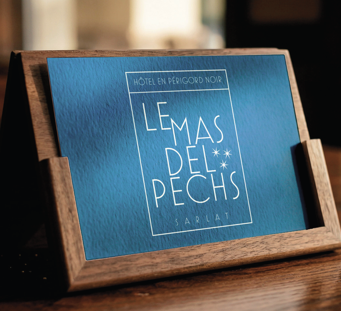 Carte bleue « Le Mas del Pechs, hôtel en Périgord Noir » sur un présentoir en bois
