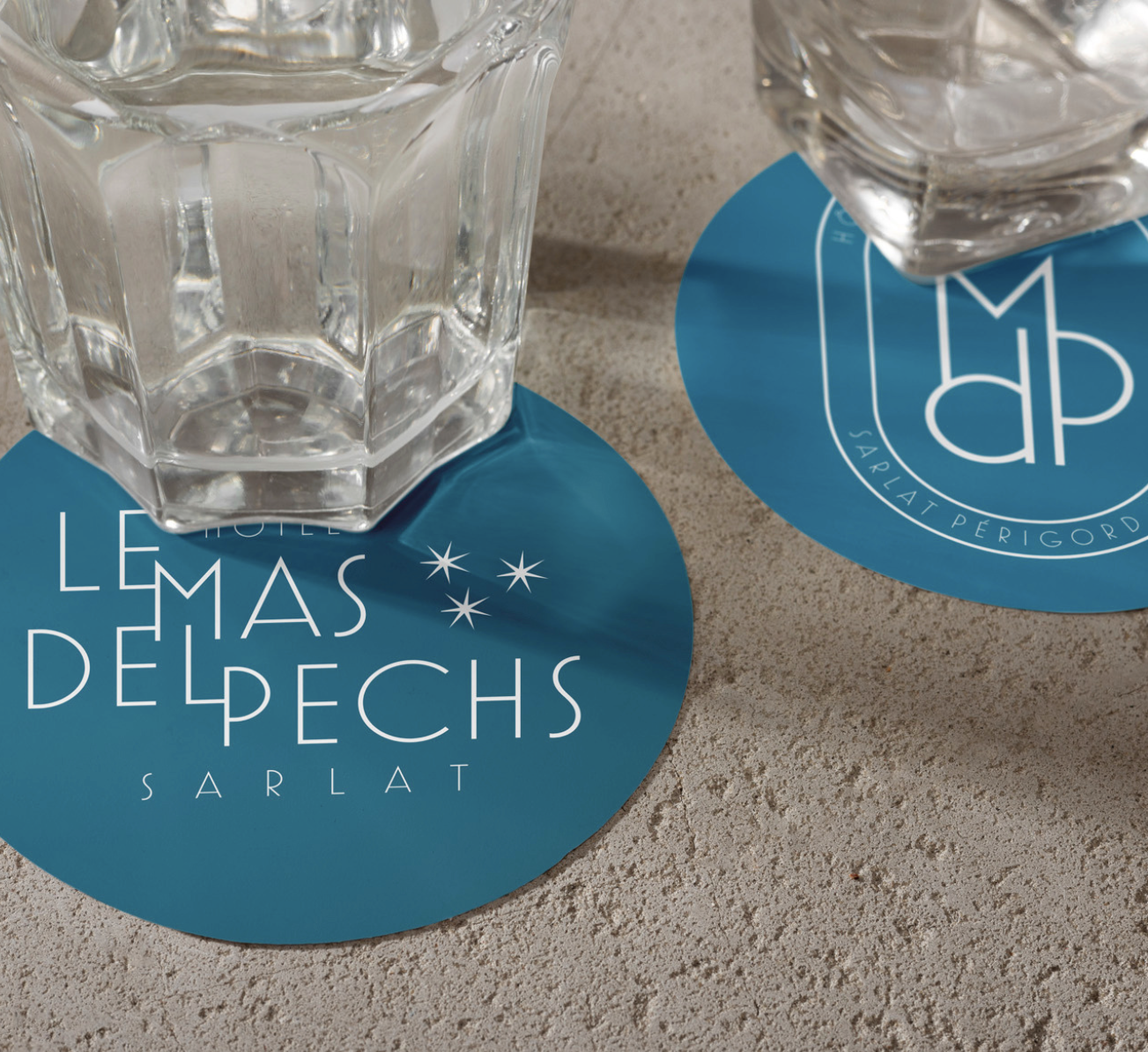 Sous-verres bleus au logo Le Mas del Pechs et à son monogramme, identité créée par ALIOKI
