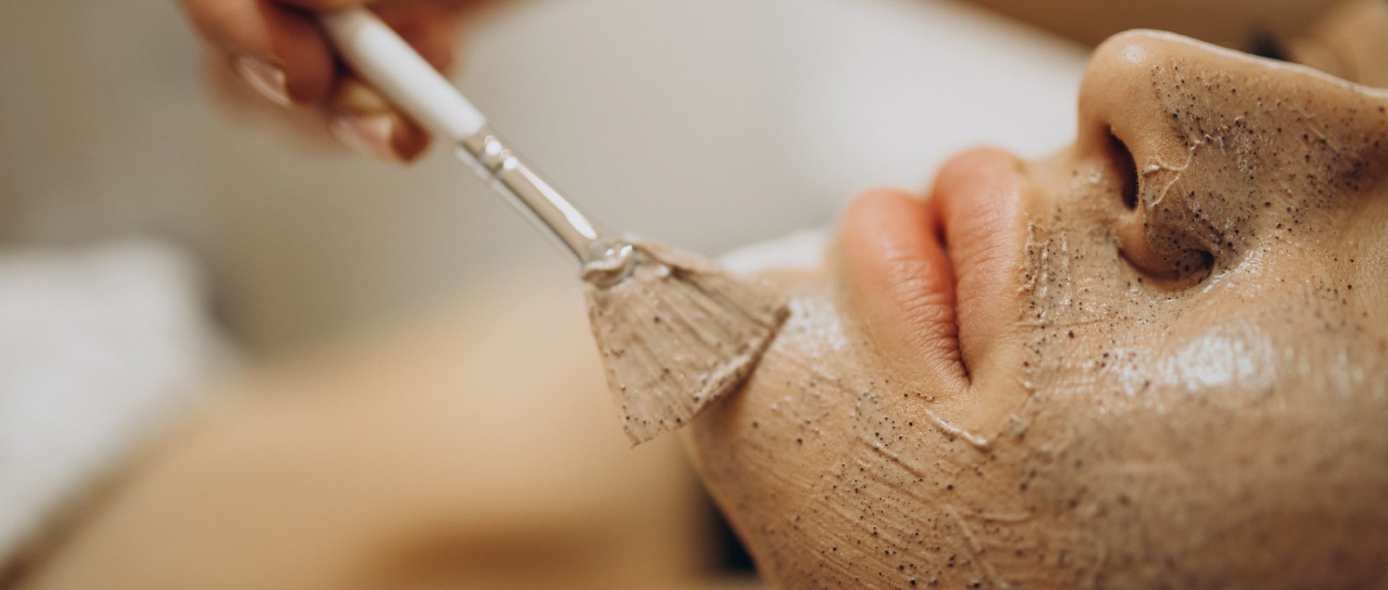 Esthéticienne appliquant au pinceau un masque sur le visage d'une cliente