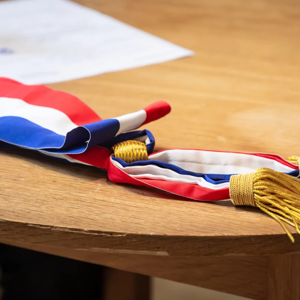 Écharpe tricolore d'élu posée sur une table de mairie