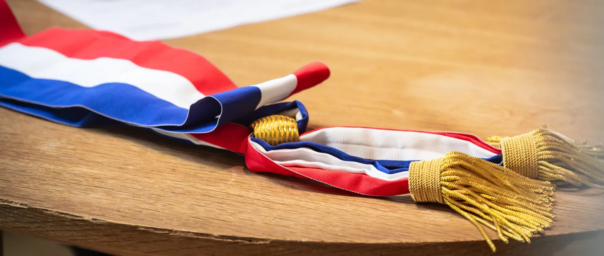 Écharpe tricolore d'élu posée sur une table de mairie